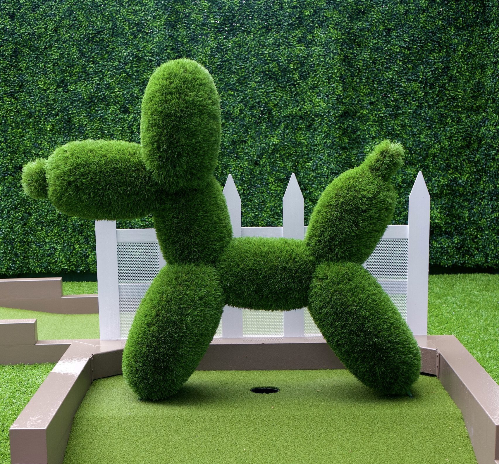 A captivating sculpture stands amid the vibrant greens of the Art Garden Mini Golf Course, blending art with play.