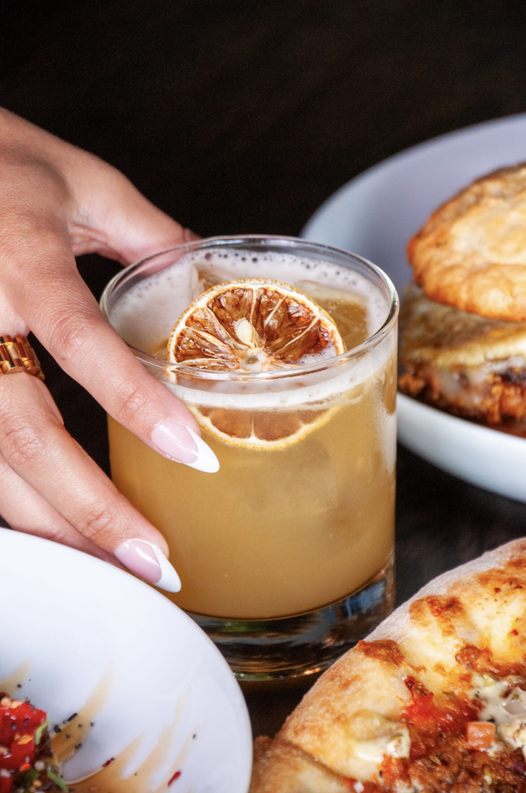 Glass of whiskey-mosa cocktail with orange slices on a sunny brunch table