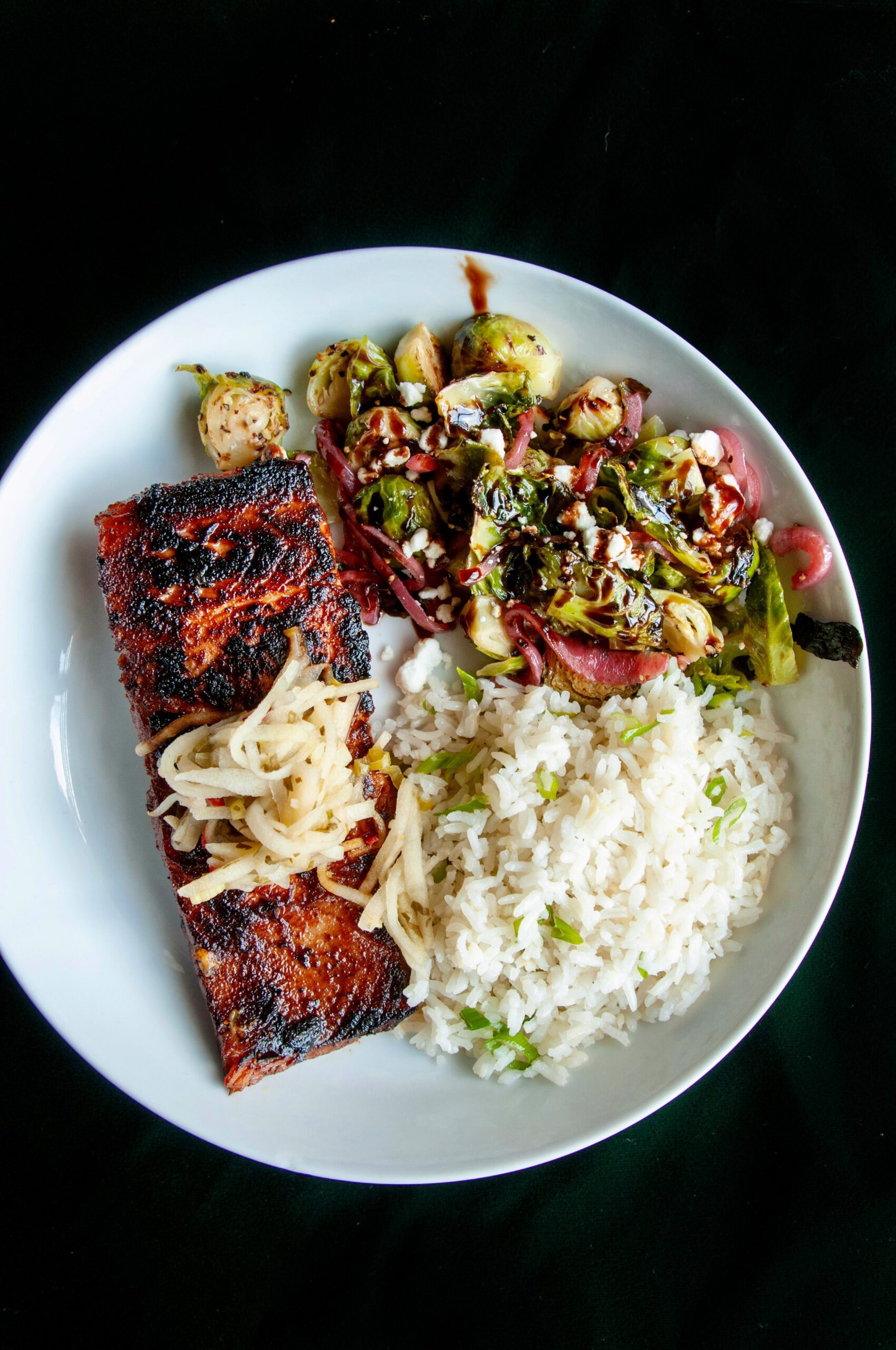 Close-up of miso glazed salmon on a bed of sautéed spinach, served on a white plate at Puttery.