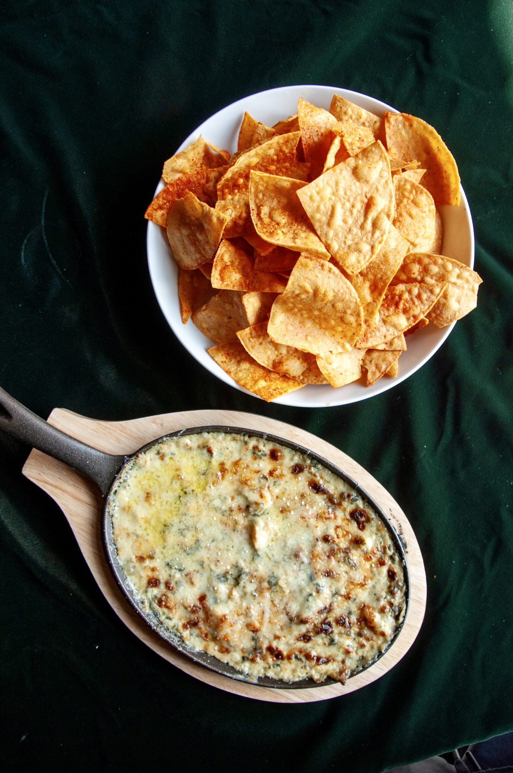 Overhead shot of a bowl full of spinach artichoke dip with chips arrayed around it on a rustic table at Puttery.